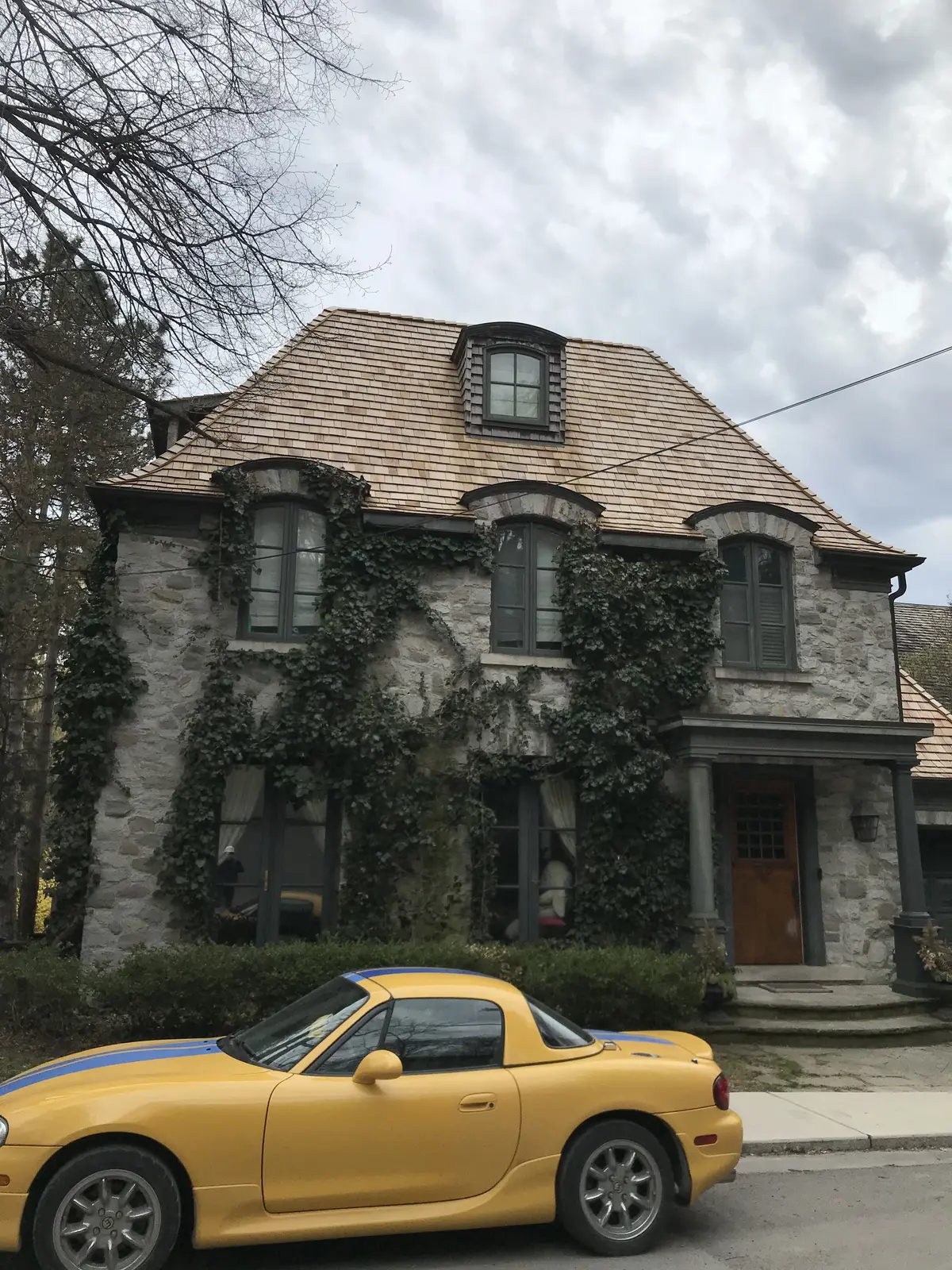 Stone chateau-style home with a cedar shake roof and dormers