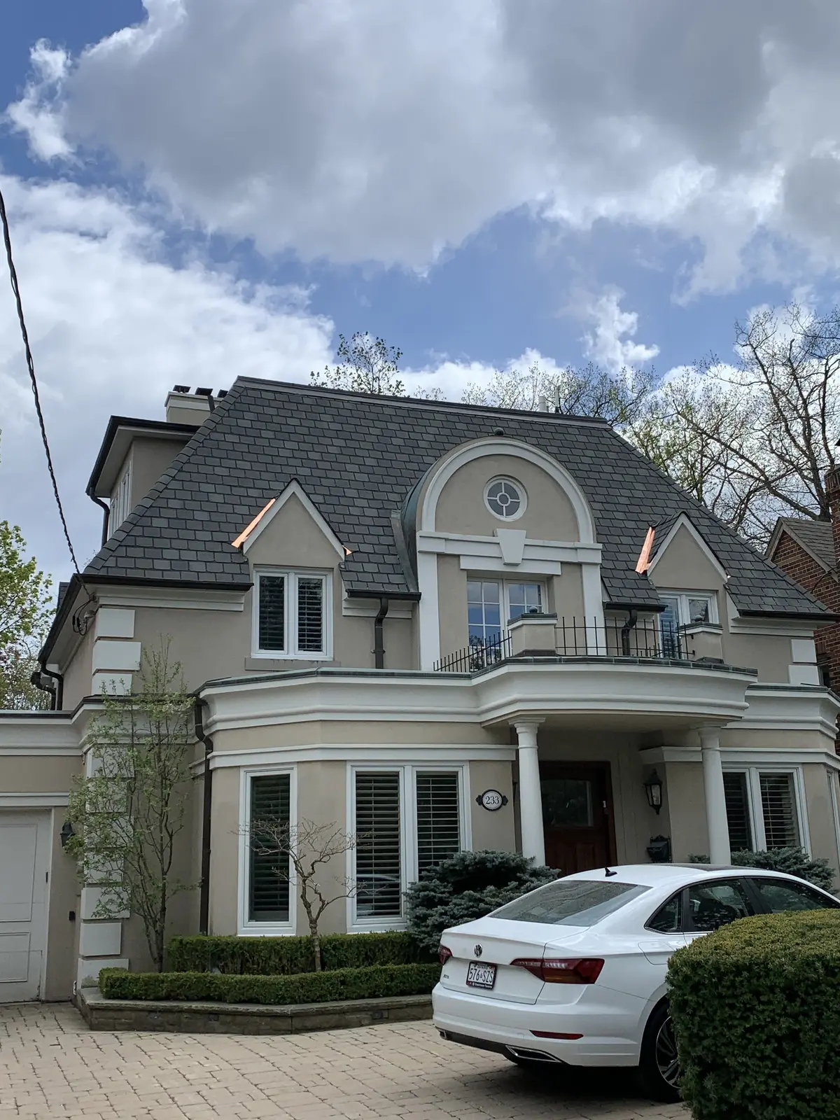 Classic two-storey home with a dark roof and a round dormer window