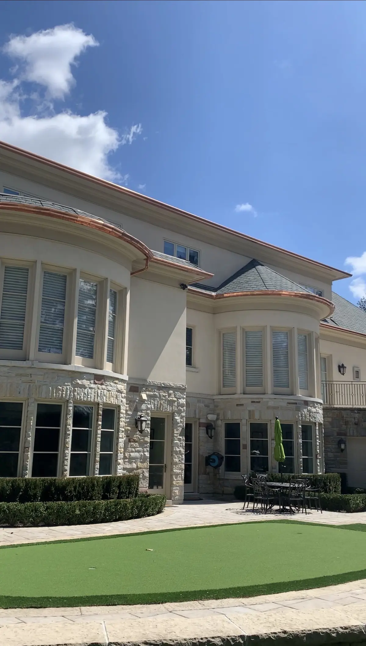 Stucco estate home with copper roof details over the bay windows