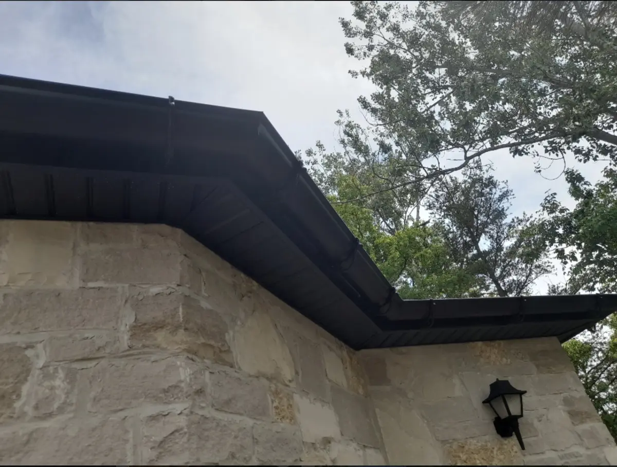 Black fascia and eavestrough along a stone wall