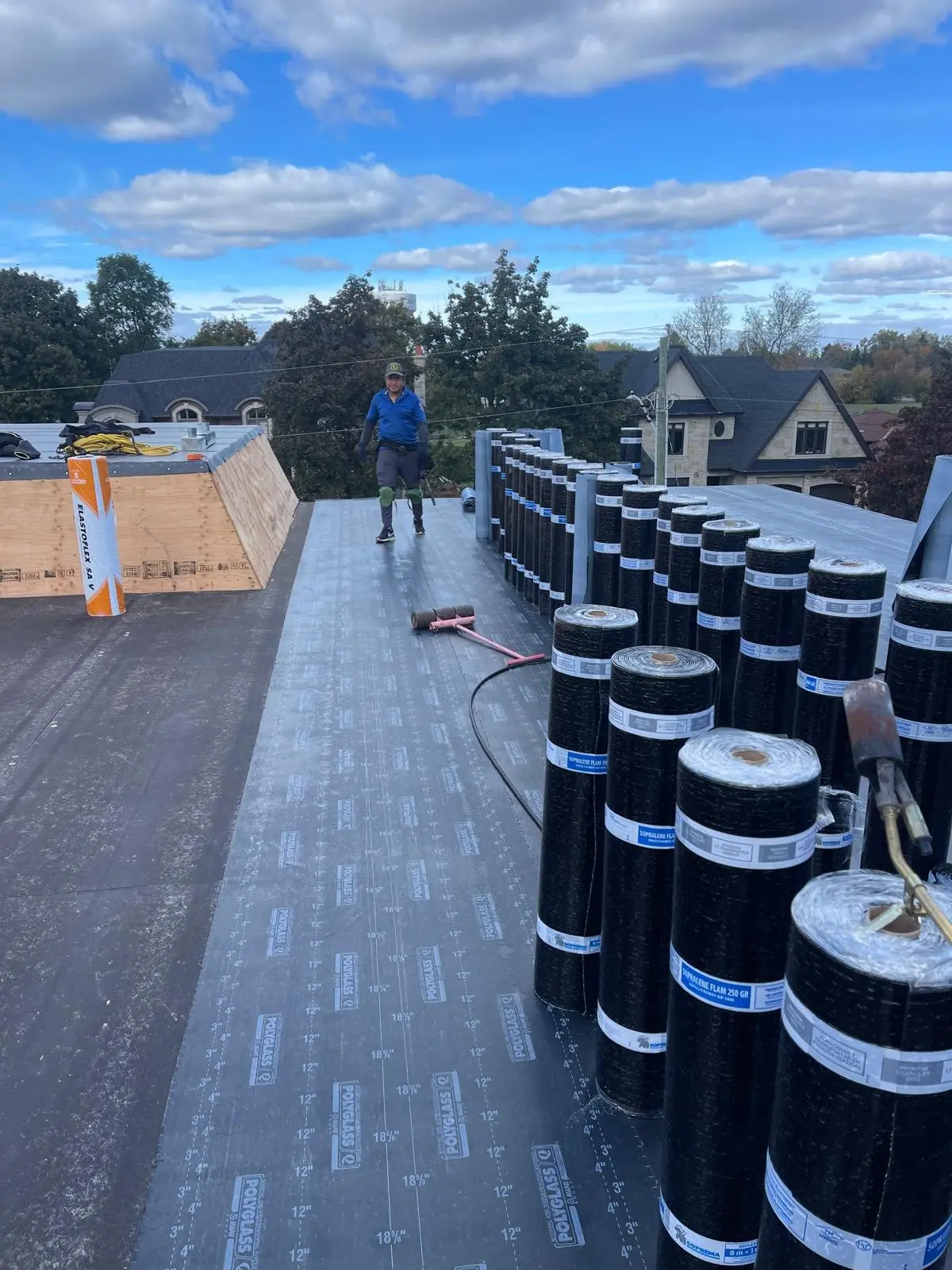Rolls of roofing membrane lined up on a flat roof during installation