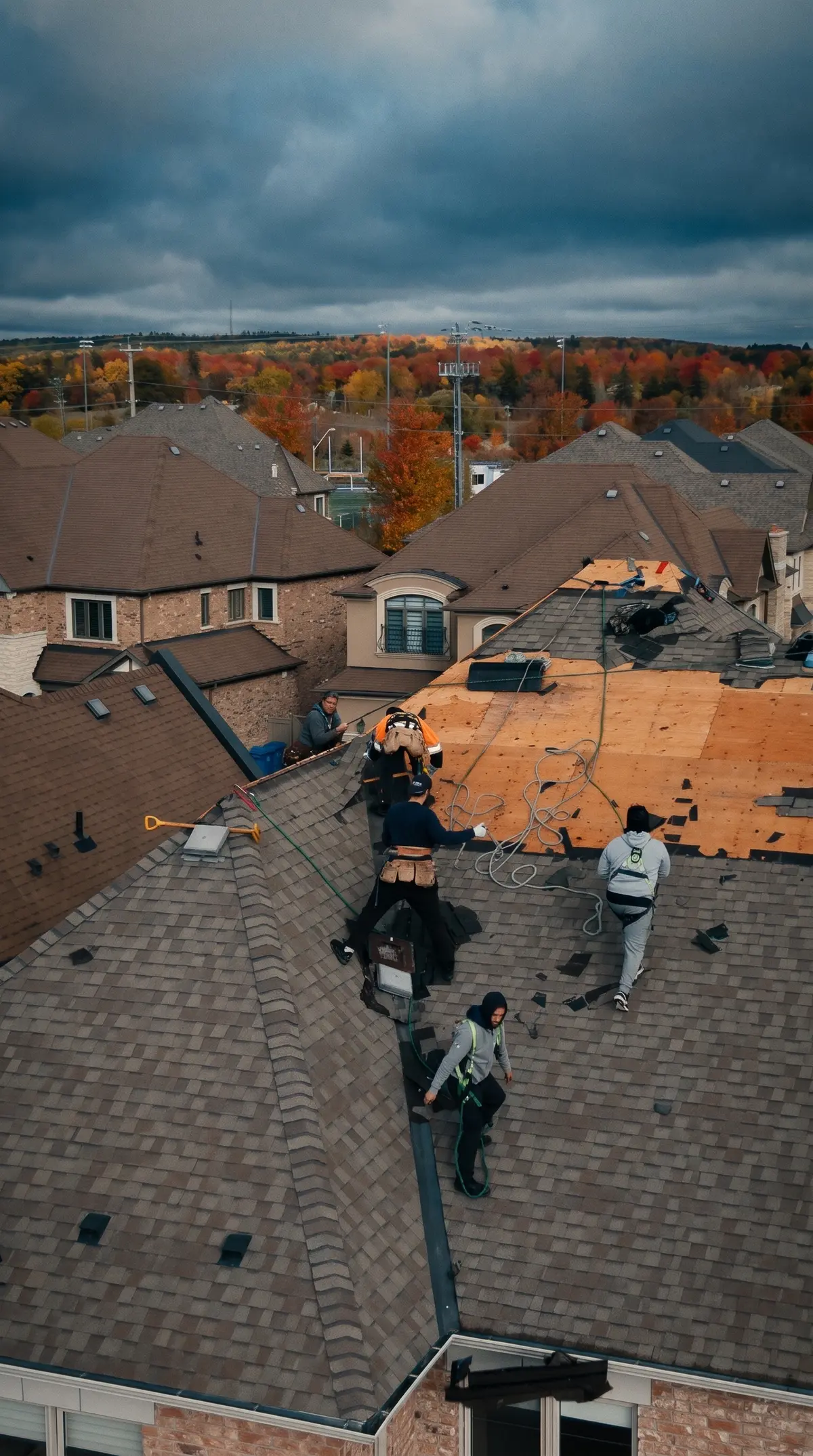 The King City roof mid-job: old shingles off one side, wood deck showing, crew on the slope