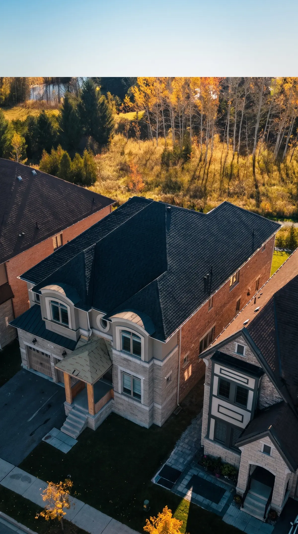 King City home from above with the new dark shingle roof, woods behind