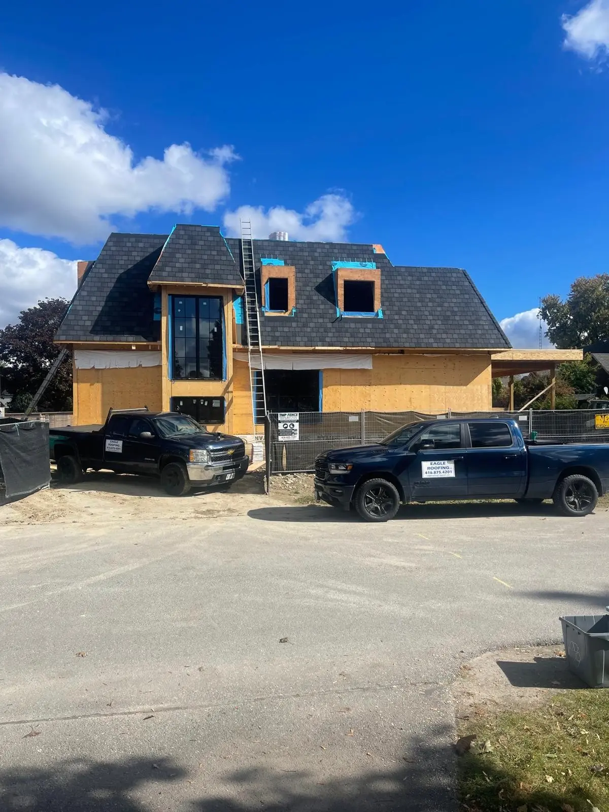 New home with a fresh shingle roof, Eagle Roofing trucks in the driveway