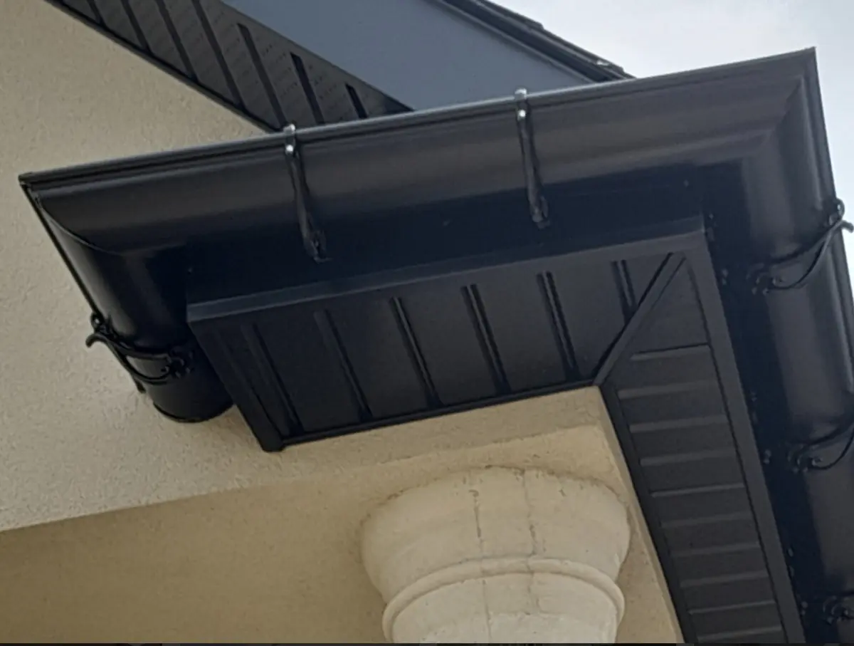 New black soffit, fascia and eavestrough at a roof corner over a column