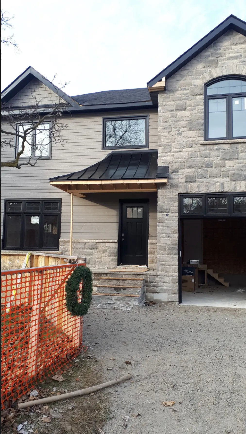 New stone home with a metal roof over the front entry